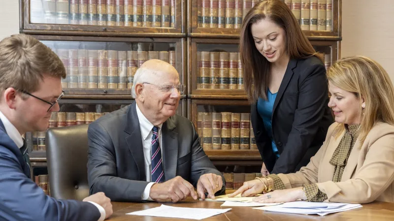 Four people in a meeting, discussing documents at a table in an office.
