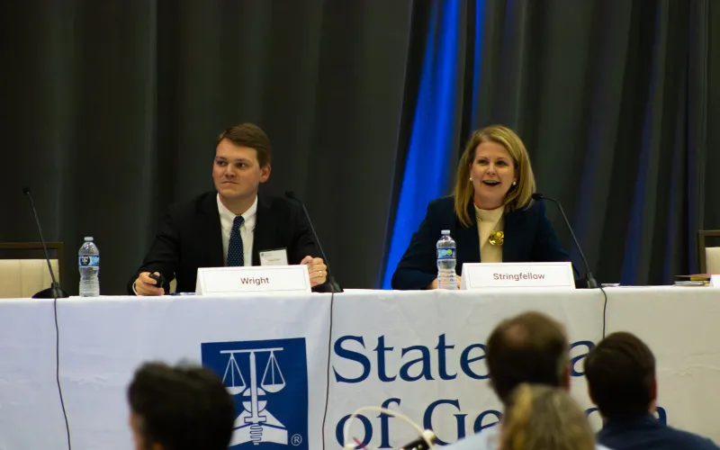 Two people sitting at a panel table labeled "State of Georgia."