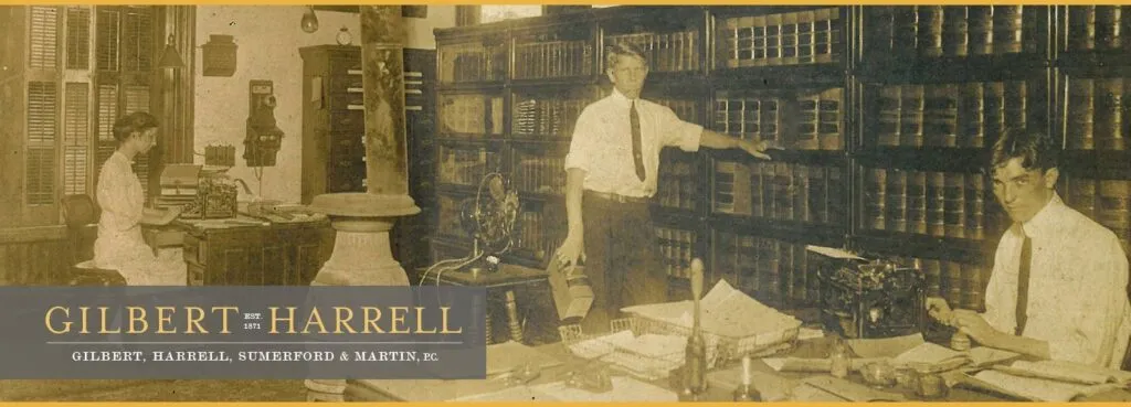 Sepia-toned photo of a vintage office with three men, shelves of books.